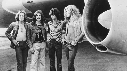 A black and white HD wallpaper featuring the band Led Zeppelin, with four members standing confidently near a large aircraft engine.
