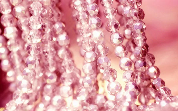 Close-up of shimmering pink beaded necklace strands, showcasing the brilliance of man-made jewelry, set against a soft pink background for an elegant HD desktop wallpaper.