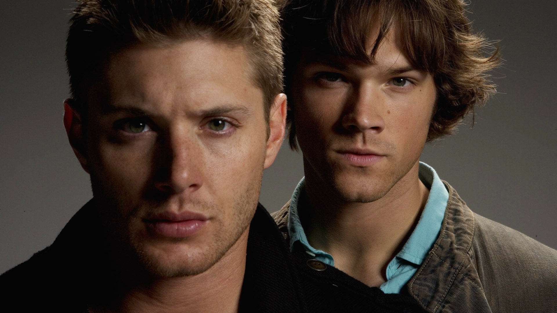 A high-definition wallpaper featuring characters from the TV show Supernatural, showcasing their intense expressions against a dark backdrop.
