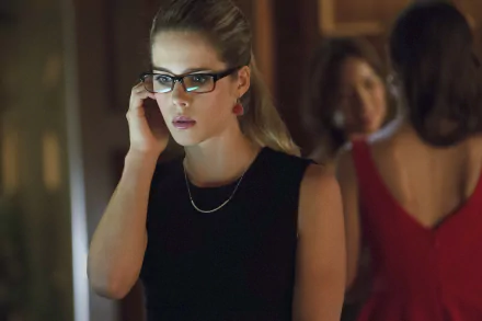 Felicity Smoak, portrayed by Emily Bett Rickards in Arrow, is shown in a focused moment wearing glasses and a black sleeveless top in this HD desktop wallpaper.