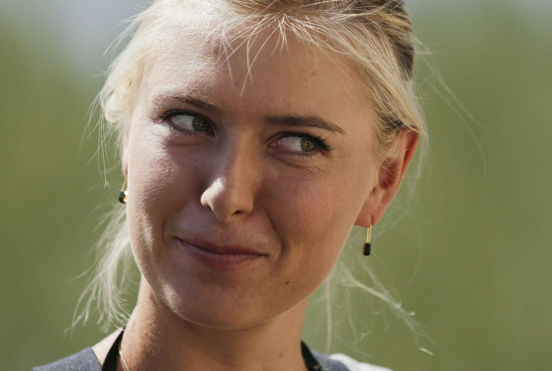 Close-up HD desktop wallpaper of Maria Sharapova with a subtle smile, set against a soft green sports-themed background.