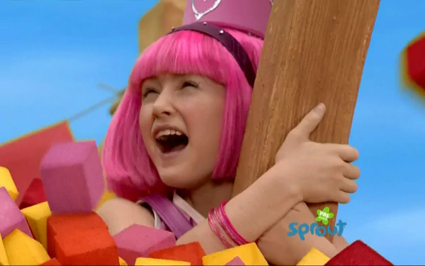 HD PC desktop wallpaper of a pink‑haired LazyTown character laughing among colorful foam blocks, hugging a wooden beam with a bright blue sky background.