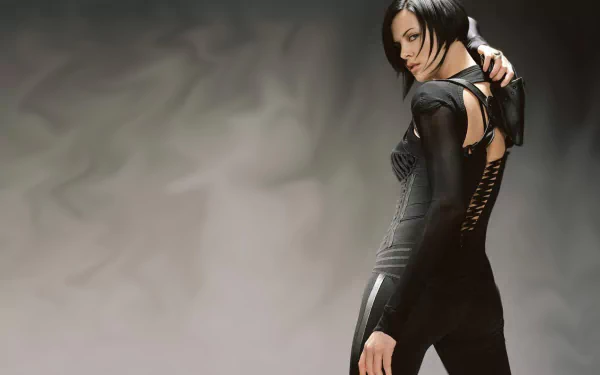 Charlize Theron in a striking pose from the movie Aeon Flux, showcasing her character's dynamic style in an atmospheric backdrop. HD wallpaper for a bold statement.