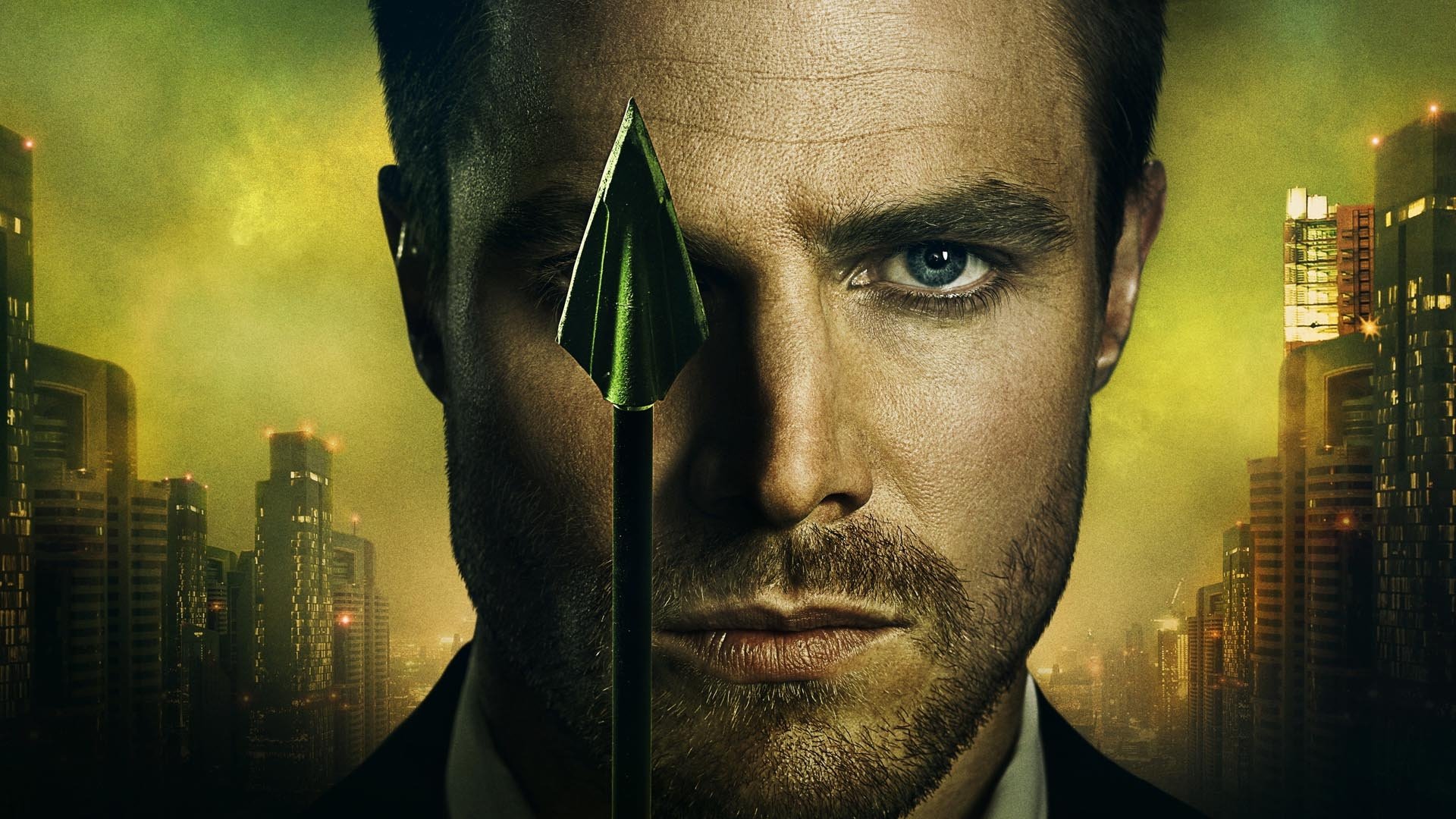HD desktop wallpaper featuring Stephen Amell as the Arrow from the TV show Arrow, with a cityscape background and a prominent arrowhead in the center.