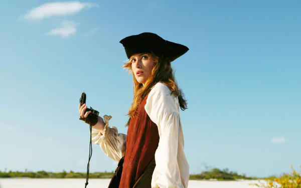 Elizabeth Swann, portrayed by Keira Knightley, gazes confidently into the distance, holding a compass against a bright blue sky in this vibrant scene from *Pirates of the Caribbean: Dead Man's Chest*.