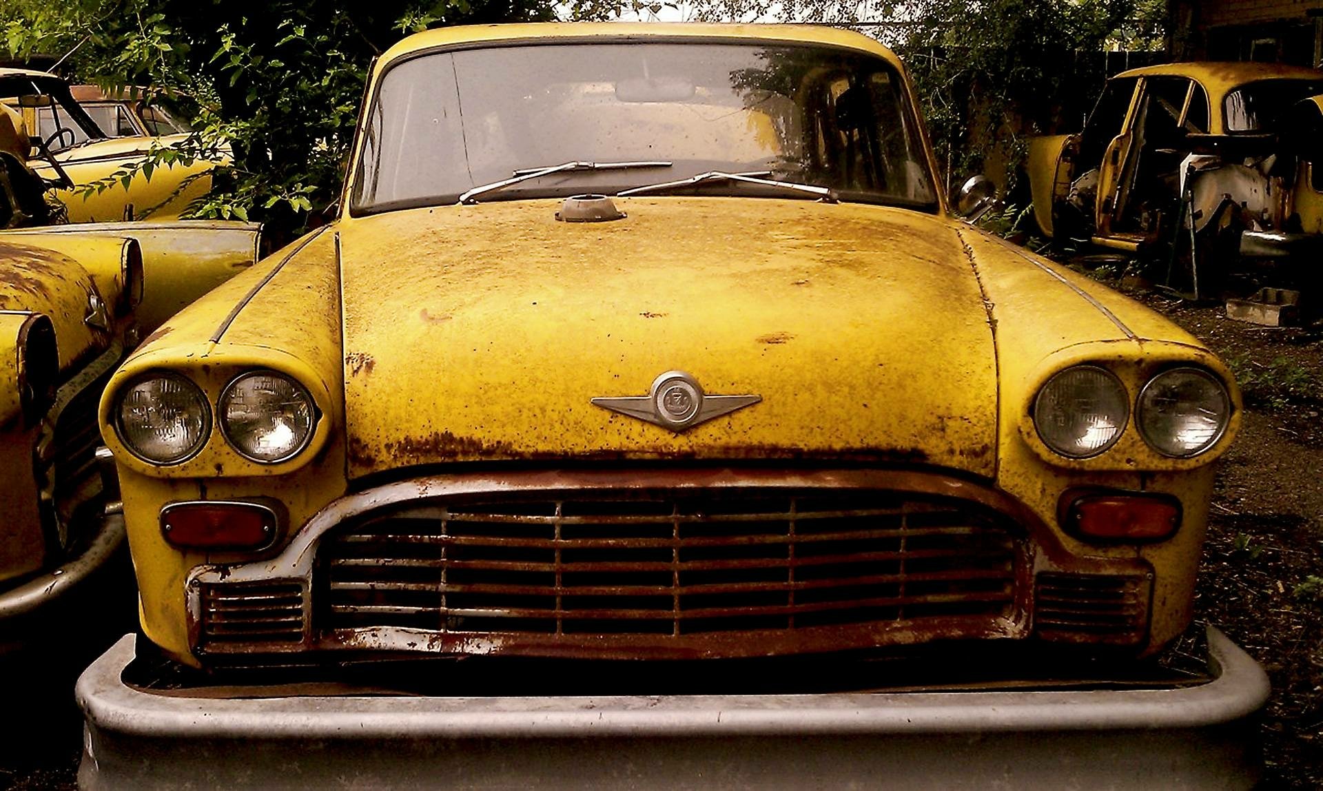 HD desktop wallpaper featuring a close-up of a vintage yellow taxi vehicle with weathered paint and classic design details.