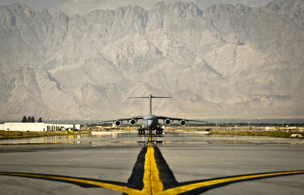 Military Boeing C-17 Globemaster III centered on a runway with rugged mountains behind — HD PC desktop wallpaper and background.