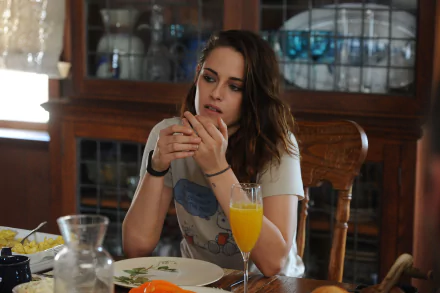 Kristen Stewart appears contemplatively at a dining table, enjoying breakfast with a glass of orange juice, from the film Still Alice. A serene domestic setting enhances the scene.