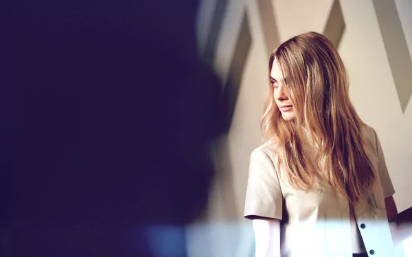 Blonde English model and actress posing thoughtfully in a soft-lit setting, captured in a high-resolution 4K Ultra HD desktop wallpaper background.