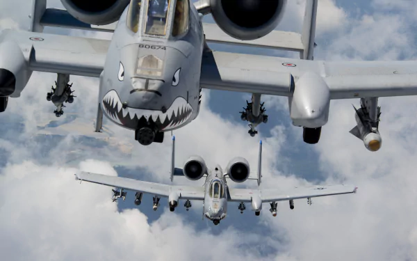 A striking HD desktop wallpaper featuring two Fairchild Republic A-10 Thunderbolt II aircraft soaring through clouds, showcasing their distinctive features and military presence.