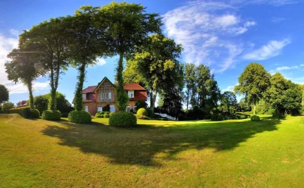 HD desktop wallpaper of a charming house surrounded by lush green lawns, tall trees, and a vibrant blue sky.