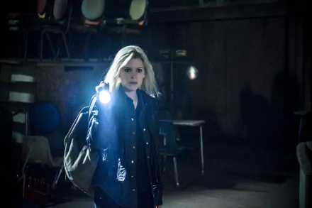 4K Ultra HD PC desktop wallpaper — dim movie still of a blonde woman holding a flashlight and shoulder bag, standing in a shadowy, empty room.