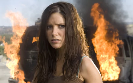 HD PC desktop wallpaper: a woman with wet hair stares ahead as a car burns behind her, still from the movie The Hitcher.