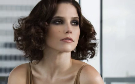 Studio portrait of a short, wavy brown-haired woman with smoky eye makeup gazing off-camera; 2K Quad HD PC desktop wallpaper/background.