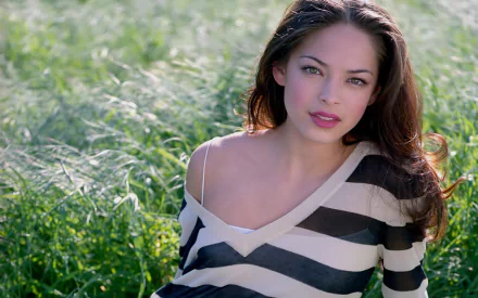 HD PC desktop wallpaper featuring celebrity Kristin Kreuk posing outdoors with a natural green background.
