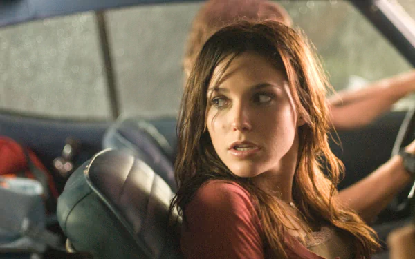 HD PC desktop wallpaper of a woman with damp hair in a car, looking over her shoulder with cinematic lighting and a moody expression.