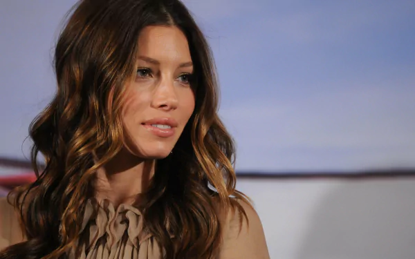 Close-up portrait of a woman with long wavy brown hair and a calm expression against a soft blue-gray backdrop — 2K Quad HD PC desktop wallpaper/background.