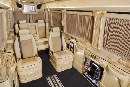 Interior of a Mercedes-Benz Sprinter van car vehicle: cream leather captain seats, wood trim, window curtains and ambient lighting, shown as an HD desktop wallpaper/background.