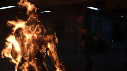 A dramatic scene from the 2015 film *Fantastic Four*, featuring a character engulfed in flames, with Kate Mara's character in action. This HD wallpaper captures intense superhero moments.