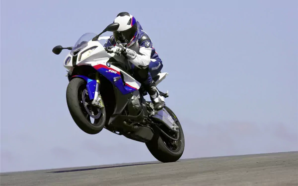 HD PC desktop wallpaper featuring a BMW S1000 motorcycle in mid-wheelie against a clear sky background.
