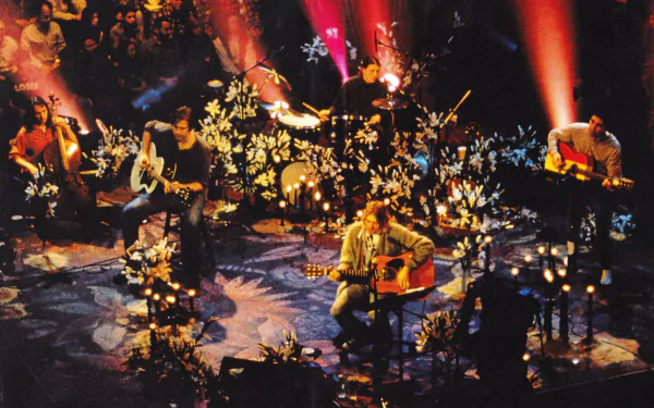 HD PC desktop wallpaper featuring Nirvana performing an acoustic set, surrounded by candles and floral decorations with warm, moody lighting.