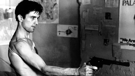 Black and white HD wallpaper featuring Robert De Niro in his iconic role from Taxi Driver, gripping a gun with intense focus in a gritty urban setting.