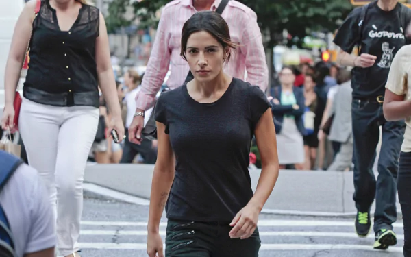 HD desktop wallpaper featuring Sarah Shahi from the TV show Person of Interest walking confidently in a busy urban setting.