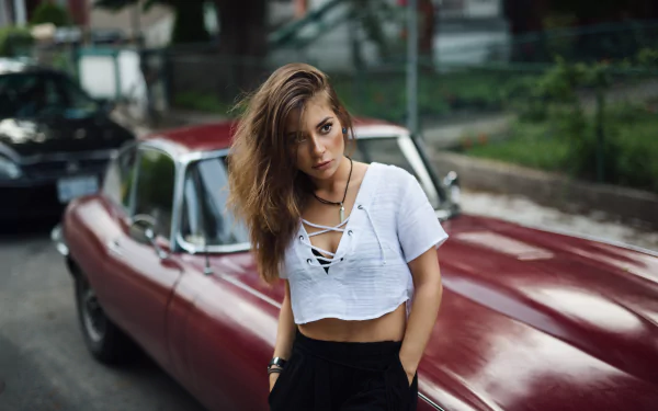 Brunette model with brown eyes leans against a red Jaguar E-Type — 5K Ultra HD PC desktop wallpaper.