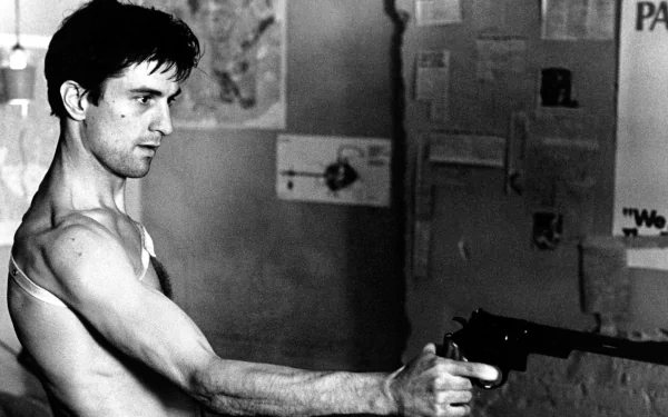 Black and white HD wallpaper featuring Robert De Niro in his iconic role from Taxi Driver, gripping a gun with intense focus in a gritty urban setting.