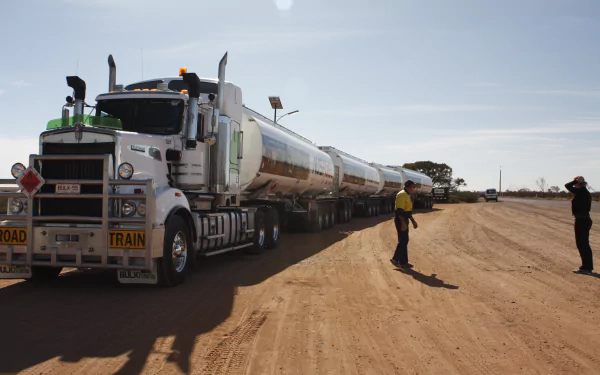 A Kenworth road train vehicle with multiple trailers parked on a dusty road under a clear sky, featured as a 4K Ultra HD PC desktop wallpaper.