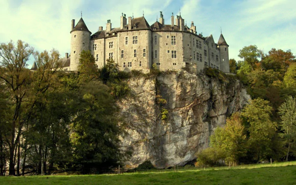 HD desktop wallpaper of Walzin Castle in Belgium, a historic man-made fortress perched atop a rocky cliff surrounded by lush greenery.