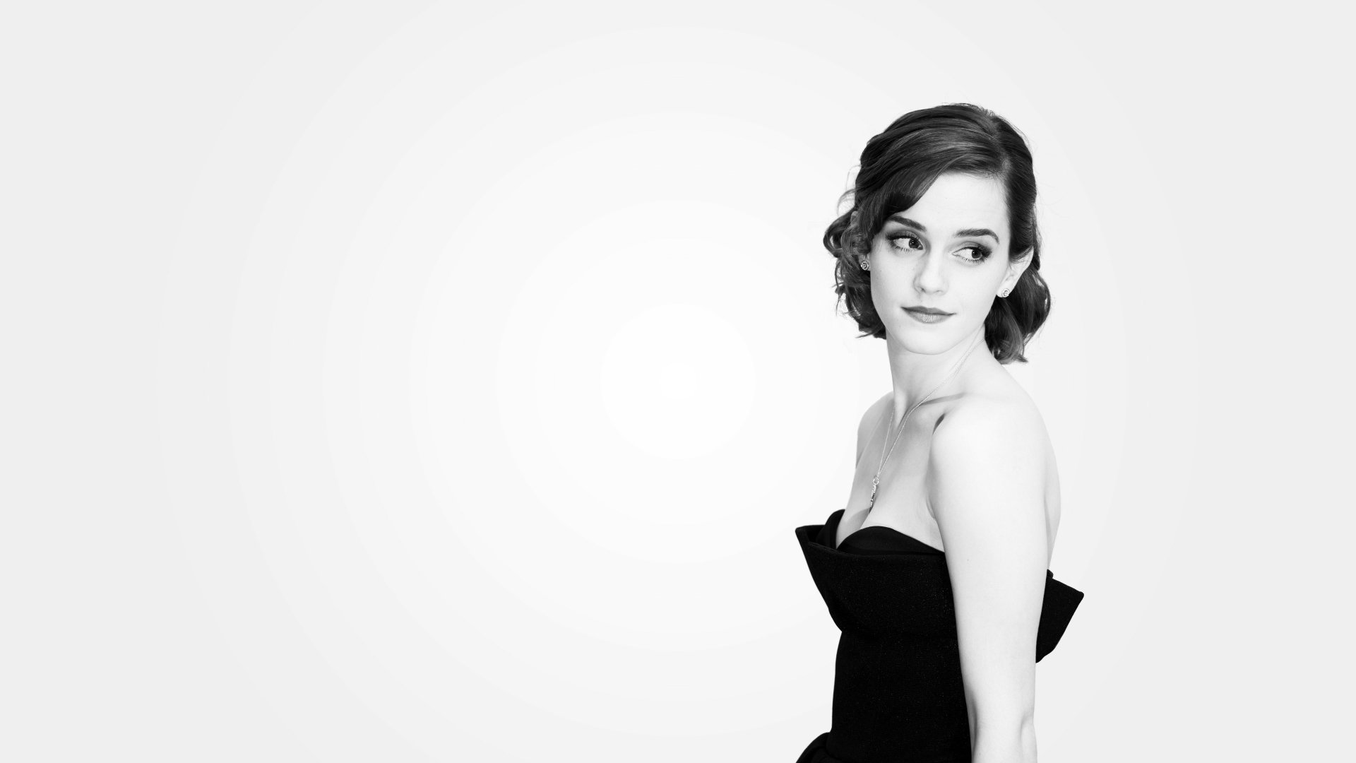Black and white 4K Ultra HD desktop wallpaper of celebrity Emma Watson in an elegant, strapless black dress against a light background.