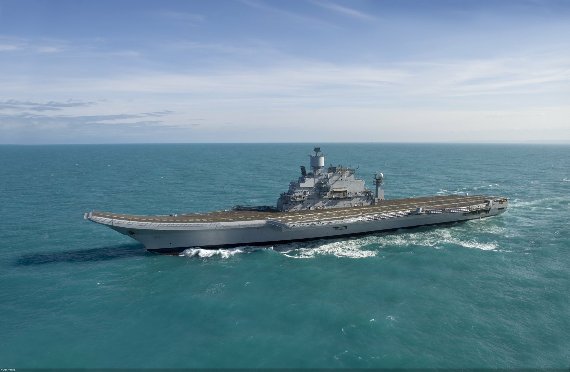 A stunning 4K Ultra HD image of the INS Vikramaditya (R33), a prominent aircraft carrier, navigating through calm waters, representing military prowess and maritime strength.