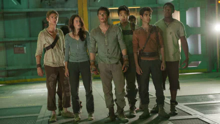 A scene from Maze Runner: The Scorch Trials featuring Dylan O'Brien, Ki Hong Lee, Kaya Scodelario, Thomas Brodie-Sangster, and others, showcasing their intense expressions in a dramatic setting.