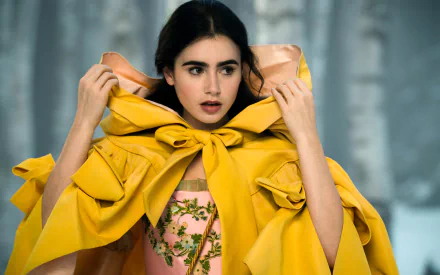 Lily Collins as the enchanting character from Mirror Mirror, dons a striking yellow cape while gazing thoughtfully, set against a whimsical backdrop in this HD desktop wallpaper.
