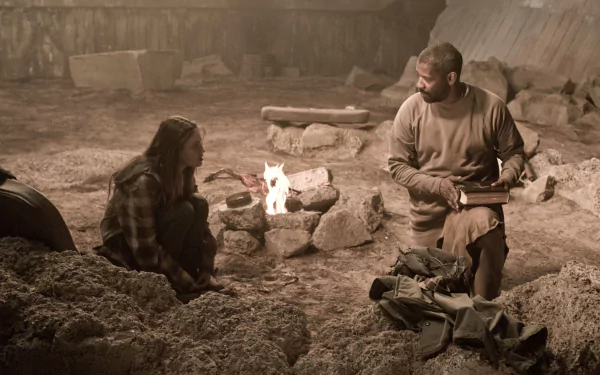 2K Quad HD PC desktop wallpaper: two actors — a man and woman — sit by a campfire in a dusty, ruined shelter in a gritty scene from the movie The Book of Eli.