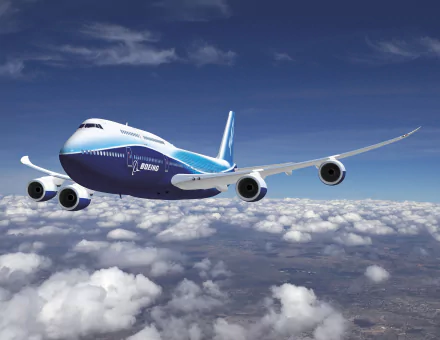 A Boeing 747 passenger plane soars above fluffy clouds, showcasing a vibrant design in an HD desktop wallpaper, ideal for aviation enthusiasts and desktop backgrounds.