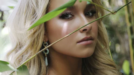 HD desktop wallpaper featuring a close-up of Hayden Panettiere in a natural, leafy setting, showcasing her cute and serene expression.