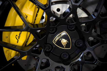 Close-up of a Lamborghini wheel featuring intricate black spokes and a golden logo, highlighting the vehicle's luxury and performance in stunning 4K Ultra HD quality.