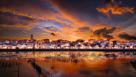HD PC desktop wallpaper featuring a vibrant sunset over a coastal town with dramatic clouds and reflections in the calm water, captured in stunning photography.