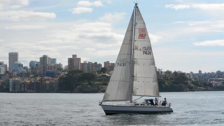 Sailboat on Sydney Harbour with city buildings along the shoreline and cloudy sky, calm water — 2K Quad HD PC desktop background showcasing Australian sailing and boat life.