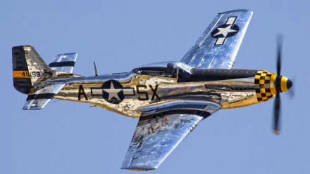 HD desktop wallpaper showing a polished North American P-51 Mustang military aircraft flying against a clear blue sky.