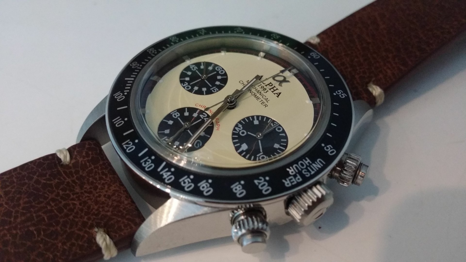 Close-up 4K Ultra HD image of a man-made wristwatch with a cream dial, black subdials, and brown leather strap on a light background.