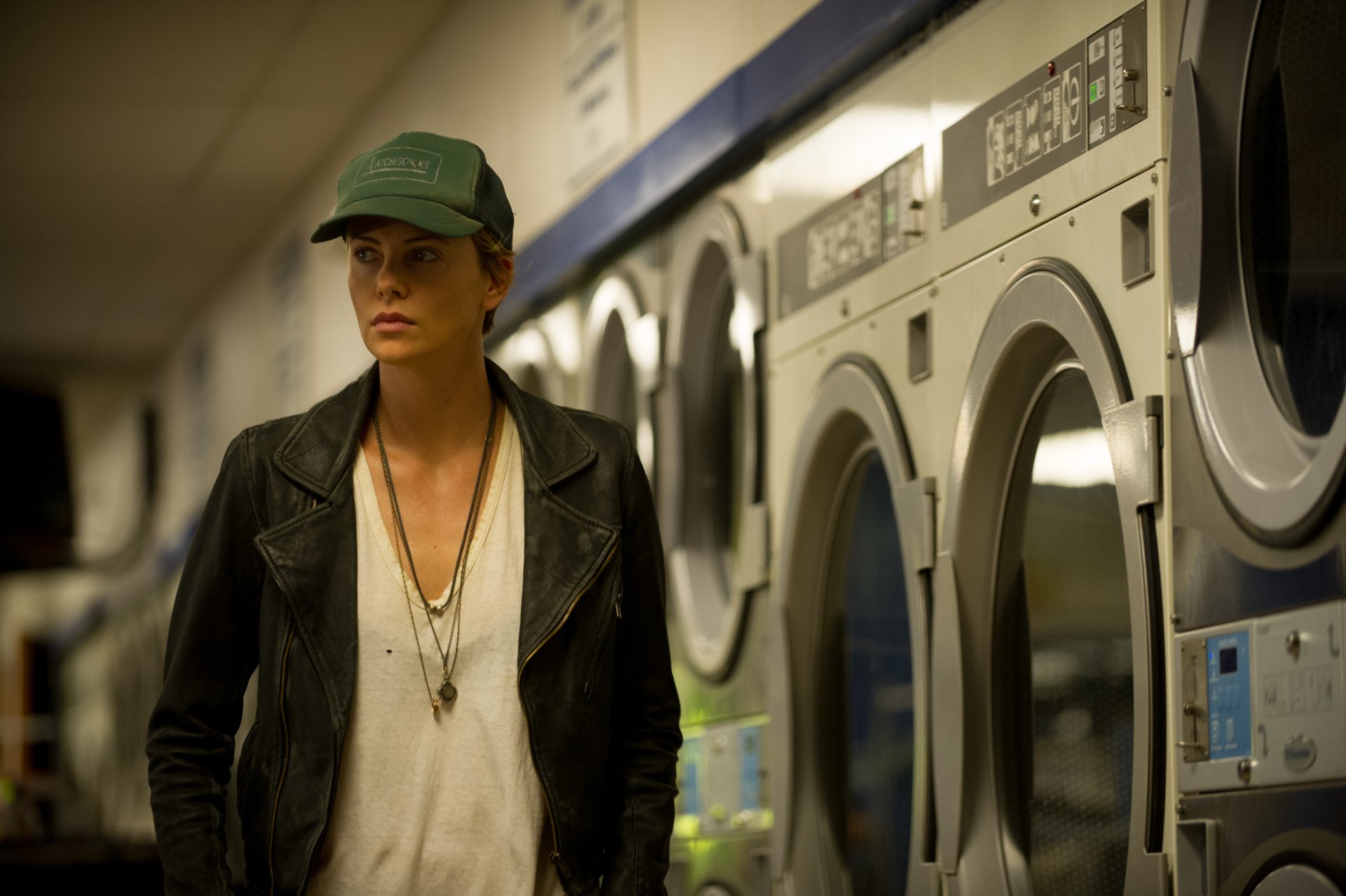 Charlize Theron in a scene from the movie Dark Places, captured in a 4K Ultra HD PC desktop wallpaper featuring a dimly lit laundromat setting.