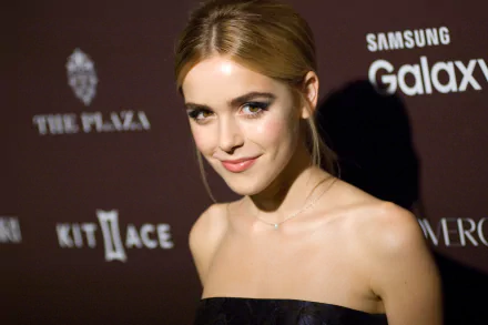 2K Quad HD PC wallpaper: portrait of a young female celebrity smiling in a strapless black dress, hair pulled back, warm lighting against a dark event-branded backdrop.