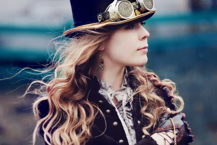 A steampunk-inspired woman with long, flowing hair wears a stylish top hat and goggles, set against a blurred background, creating an intriguing sci-fi atmosphere in this HD wallpaper.