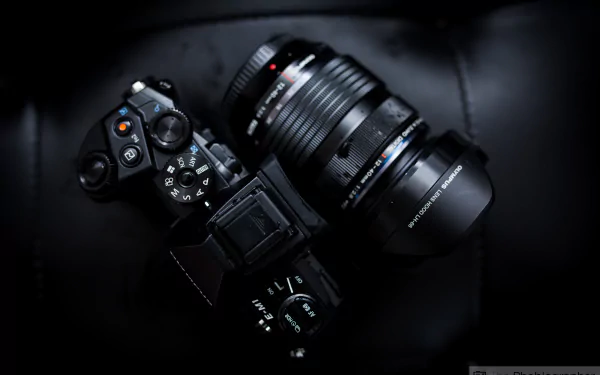 Close-up of an Olympus camera lens on a sleek, black camera, captured in high detail for a 4K Ultra HD PC desktop wallpaper background.