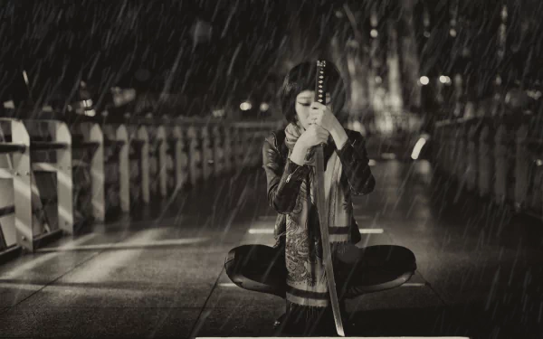 A martial artist kneeling on a rain-soaked bridge, gripping a katana, captured in a dramatic black-and-white HD desktop wallpaper.