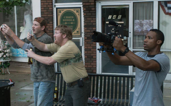 HD desktop wallpaper featuring the cast of the movie Into the Storm filming a scene outdoors with a camera and phone in front of a brick building.