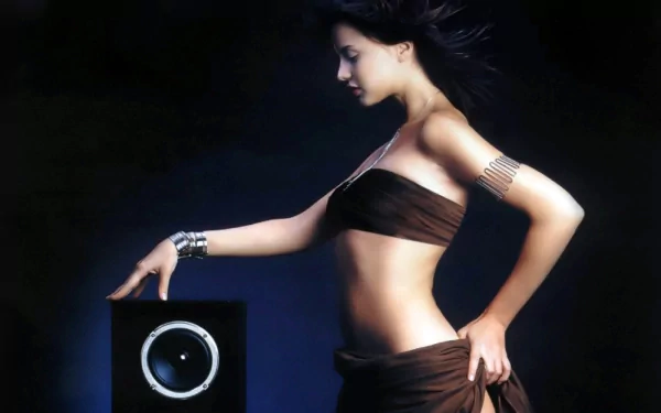 A striking HD desktop wallpaper featuring a woman in a stylish pose beside a sleek music speaker, highlighting the connection between beauty and sound.